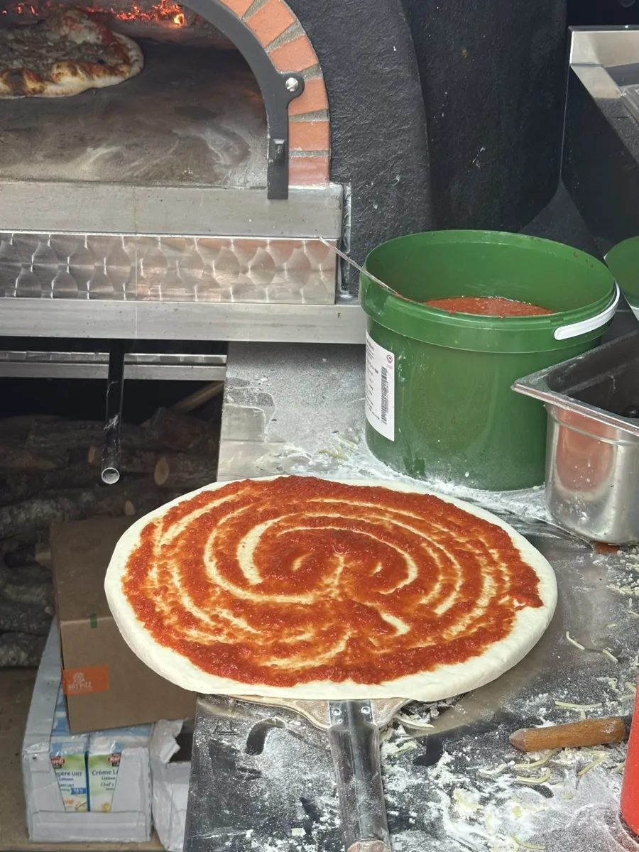 Sauce tomate maison étalée en spirale sur une pâte à pizza