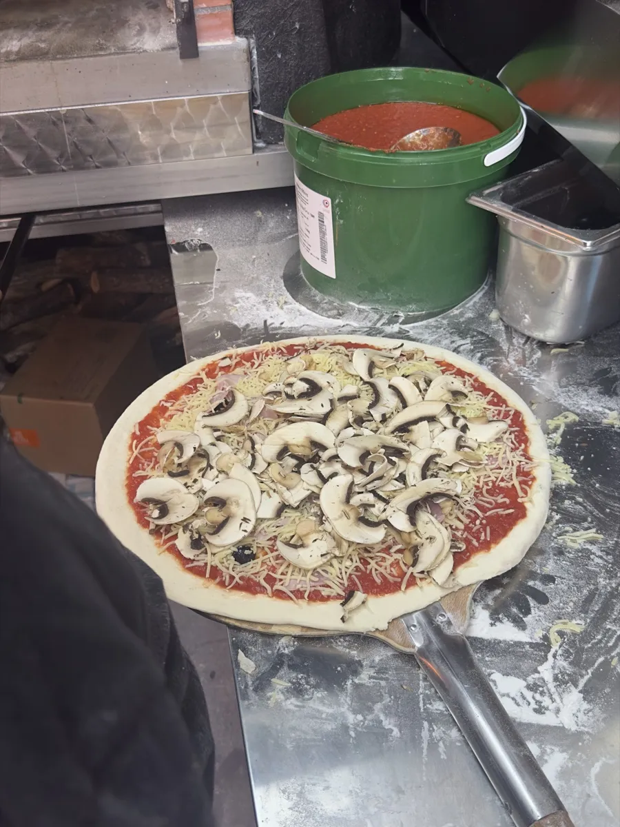 Une pizza cuite et gratinée sort du four à bois