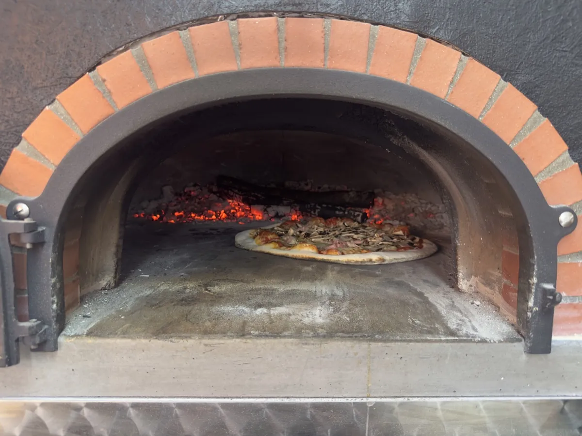 Une pizza glisse sur la pelle dans le four à bois